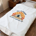 Blanket with 'He is Risen, I'm Still Waking Up' design draped over a bed.