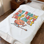White blanket with colorful graphic of a brain and text on a bed in a bedroom.