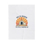 White towel with 'He is Risen, I'm Still Waking Up' design featuring a tomb and cross.